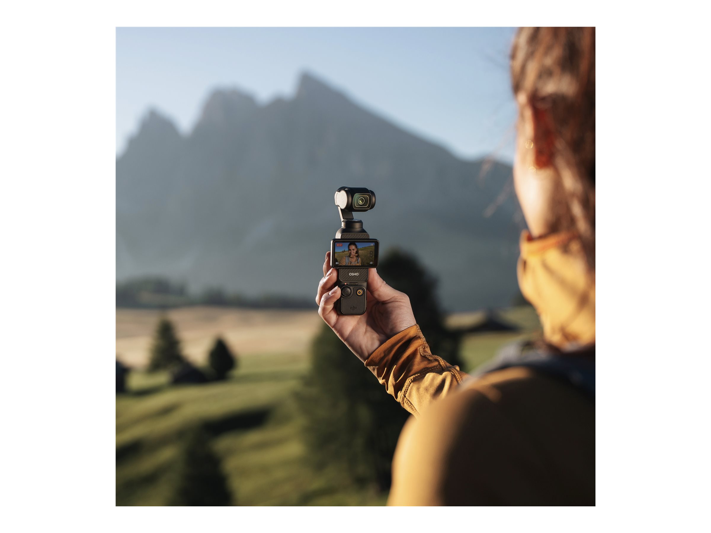 Hand som håller DJI Osmo Pocket 3 framför bergslandskap