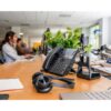 Poly Voyager 4320 headset bredvid bordstelefon och laddningsställ